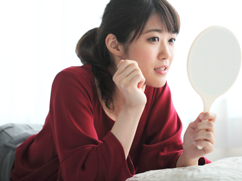 女性が鏡で自分の歯を見ている