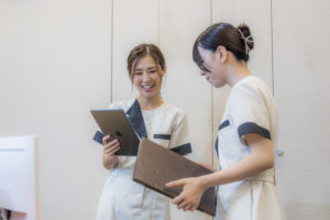 あゆみ歯科クリニックのスタッフ2名が院内で情報共有をしているところ
