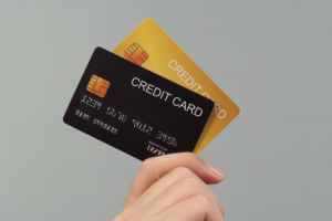 クレジットカードのイメージ。グレーの背景で手にクレジットカードを持っている様子