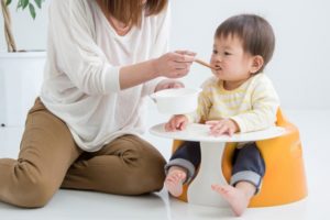 離乳食を食べる赤ちゃんのイメージ。母親が食べさせている様子。