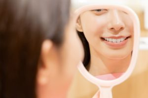 歯並びの良いイメージ。女性が自身の綺麗な歯並びを眺めているところ